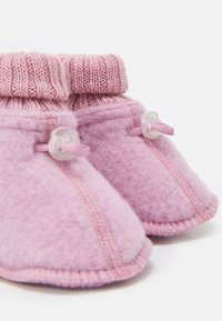 Rosa ulltofflor med en stickad krage, som har en slät textur, dekorativa knappar och en mjuk, rundad form.