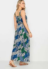 Abito lungo con una stampa colorata di felci in blu, verde e bianco. Realizzato in tessuto leggero con spalline larghe, vestibilità comoda e lunghezza fino alla caviglia.