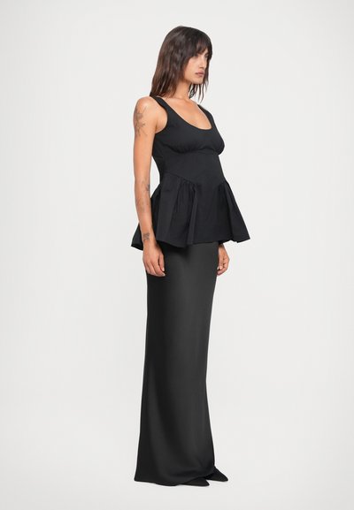 Black peplum top with a fitted bodice and ruffled hem, paired with a form-fitting black skirt. Smooth texture, minimalist design.