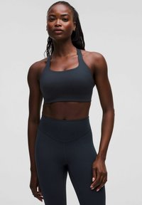 Mörkgrå sportbh med fyrkantig halsringning och tjocka axelremmar, i kombination med högmidjade mörkgrå tights, slät textur, åtsittande design.