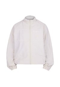 Giacca leggera di colore crema con colletto alto, zip frontale, polsini elasticizzati e dettagli di cucitura visibili attraverso il petto.