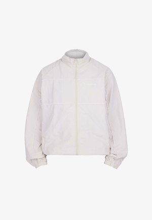 Viegls, krēmkrāsas mētelis ar augstu apkakli, priekšējo rāvējslēdzēju, elastīgām aprocēm un redzamām šuvēm pa krūšu daļu.