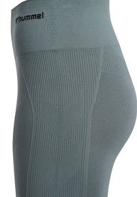 Leggings verdi con una vita alta, dotati di una texture a coste e di motivi diagonali. Logo del marchio visibile sulla vita.