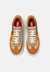 Sneaker beige e marroni con accenti arancioni, caratterizzati da un design in materiali misti, lacci piatti e una suola in gomma bianca. Marchio CAMPR visibile.