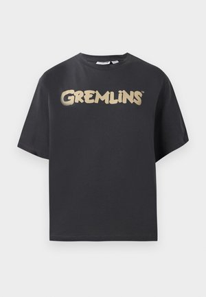 Melnas īsām piedurknēm t-krekls, izgatavots no kokvilnas, ar izteiktu zelta "GREMLINS" logotipu krūtīs rotaļīgā fontā.