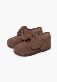 Chaussures en suede marron avec un accent de nœud, design à bout rond et semelle plate basse. Texture douce et détails de couture simples.