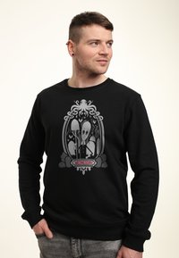 Felpa nera con una grafica di un polpo e un personaggio con una grande testa, incorniciato da dettagli di design intricati. Il testo recita "MERCOLEDÌ".