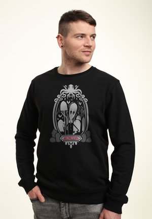 Felpa nera con una grafica di un polpo e un personaggio con una grande testa, incorniciato da dettagli di design intricati. Il testo recita "MERCOLEDÌ".