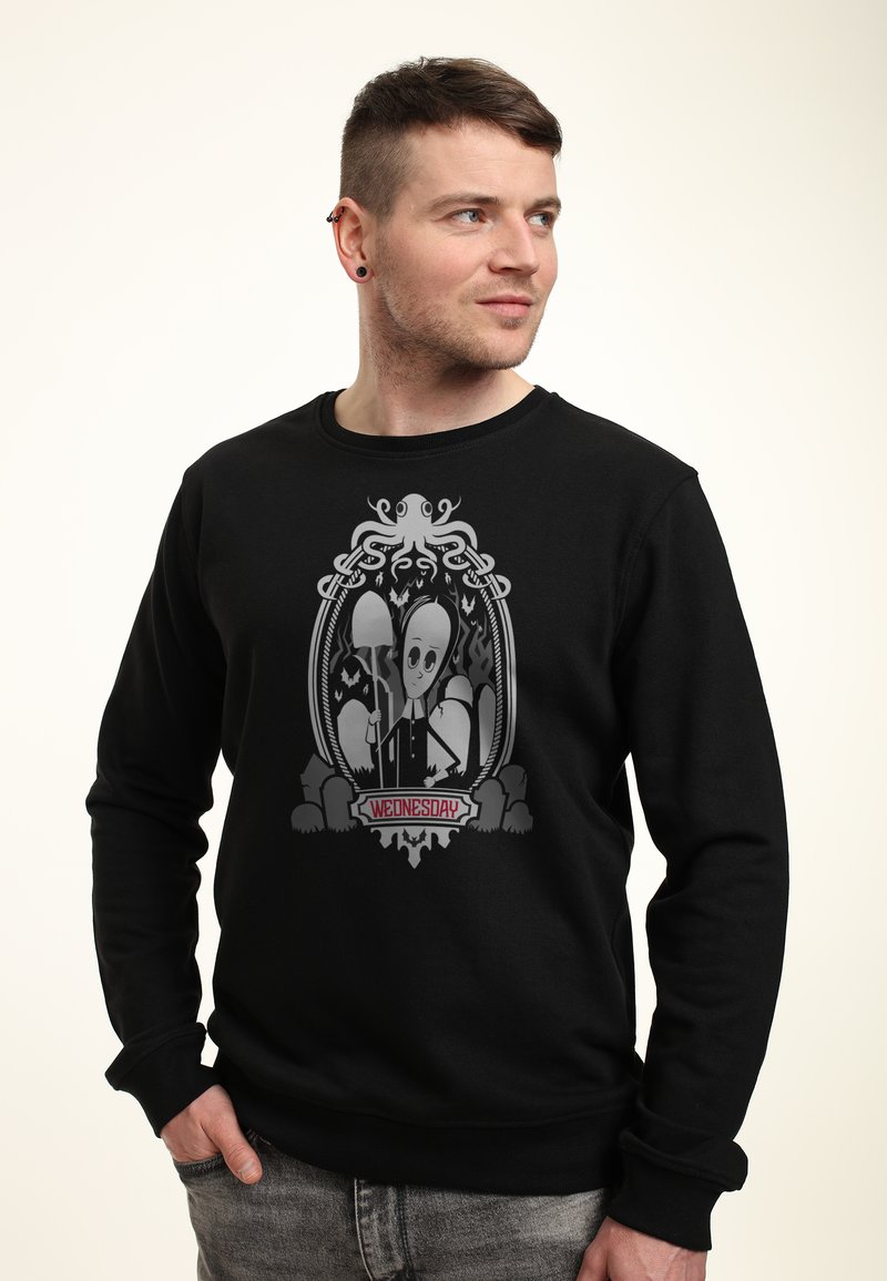Felpa nera con una grafica di un polpo e un personaggio con una grande testa, incorniciato da dettagli di design intricati. Il testo recita "MERCOLEDÌ".