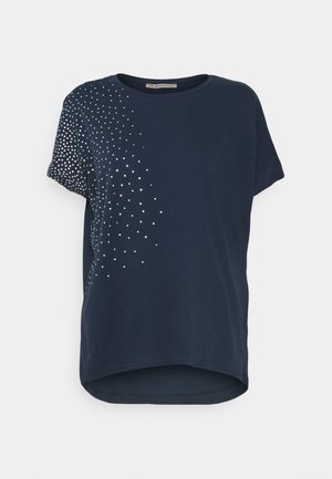 Camicia blu navy a maniche corte con motivo a pois argentati che si irradiano dalla spalla sinistra fino alla parte centrale del torso, scollatura rotonda e orlo leggermente curvato.
