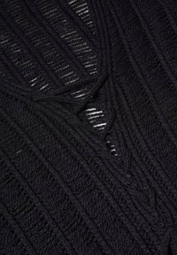 Czarna dzianina z pionowymi prążkowanymi wzorami i dekoltem w kształcie litery V. Posiada różnorodne tekstury i szczegóły z otwartym splotem.