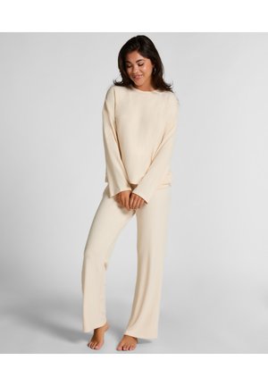 Beige Loungewear-Set mit langärmligem Oberteil und weiten Hosen, aus weichem Stoff gefertigt, mit lockerer Passform und minimalistischem Design.