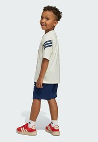 Svetlozelené tričko s námorníckymi pruhmi na rukávoch, doplnené námorníckymi šortkami a červenými topánkami. Obsahuje biele ponožky a voľný strih.