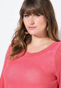 Suéter de punto rosa con un escote amplio y un patrón texturizado, que presenta mangas largas y un corte holgado.