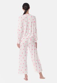 White pajama set with long sleeves and wide-leg pants, featuring a pattern of pink kiss marks, made from a soft fabric.
