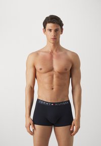 Boxer-briefs bleu marine avec une ceinture ornée du logo "TOMMY HILFIGER" en blanc, rouge et bleu. Tissu doux avec un ajustement près du corps.