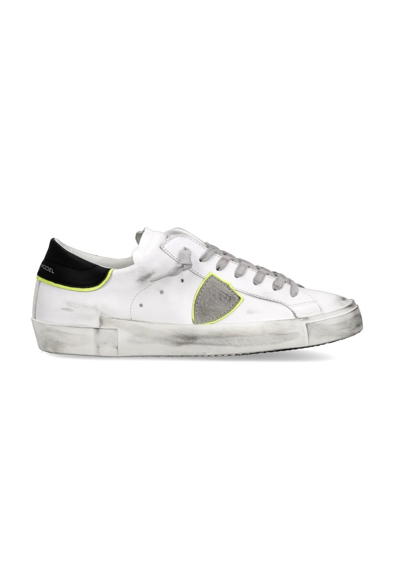 Zapatillas de cuero blancas con acentos grises, una lengüeta negra en el talón y detalles en neón amarillo. Presentan un aspecto ligeramente desgastado con detalles texturizados y un diseño clásico con cordones.