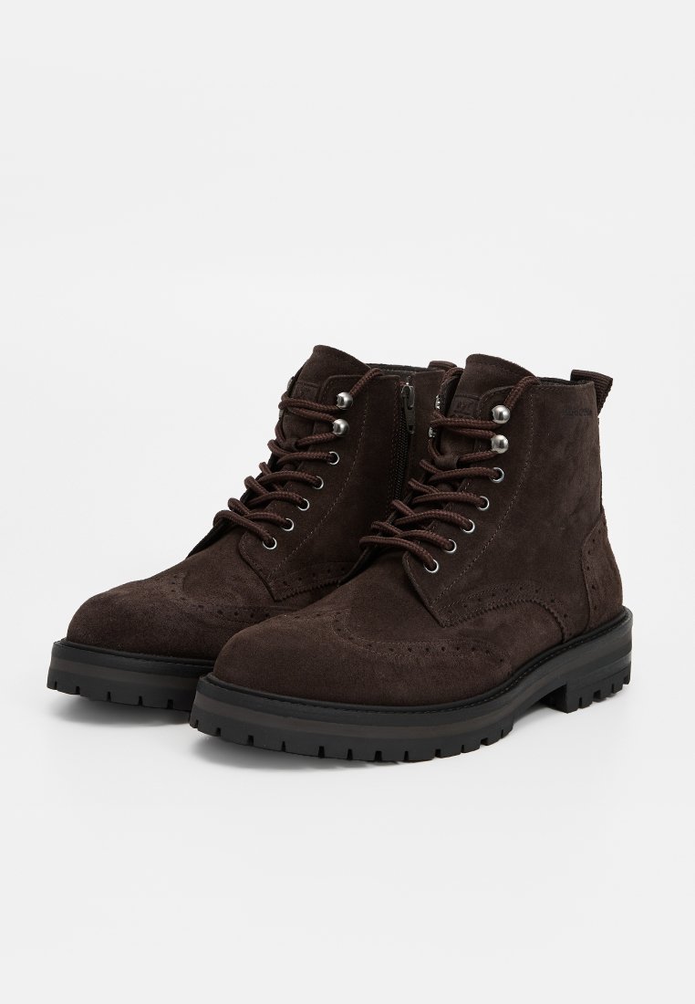 Braune Wildleder-Ankle-Boots mit Schnürung vorne, metallenen Ösen, seitlichem Reißverschluss und strukturiertem Gummisohle; verfügen über Brogue-Details an den Seiten.