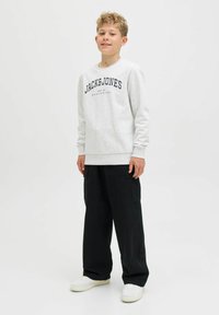 Šedá mikina s černým logem "JACK & JONES", kombinovaná s černými cargo kalhotami a bílými teniskami, se uvolněným střih a pružnými manžetami.
