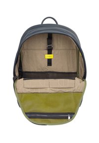 Mochila azul marino con un diseño redondeado. El interior presenta una tela beige con un patrón geométrico, un bolsillo de malla verde y una etiqueta amarilla.