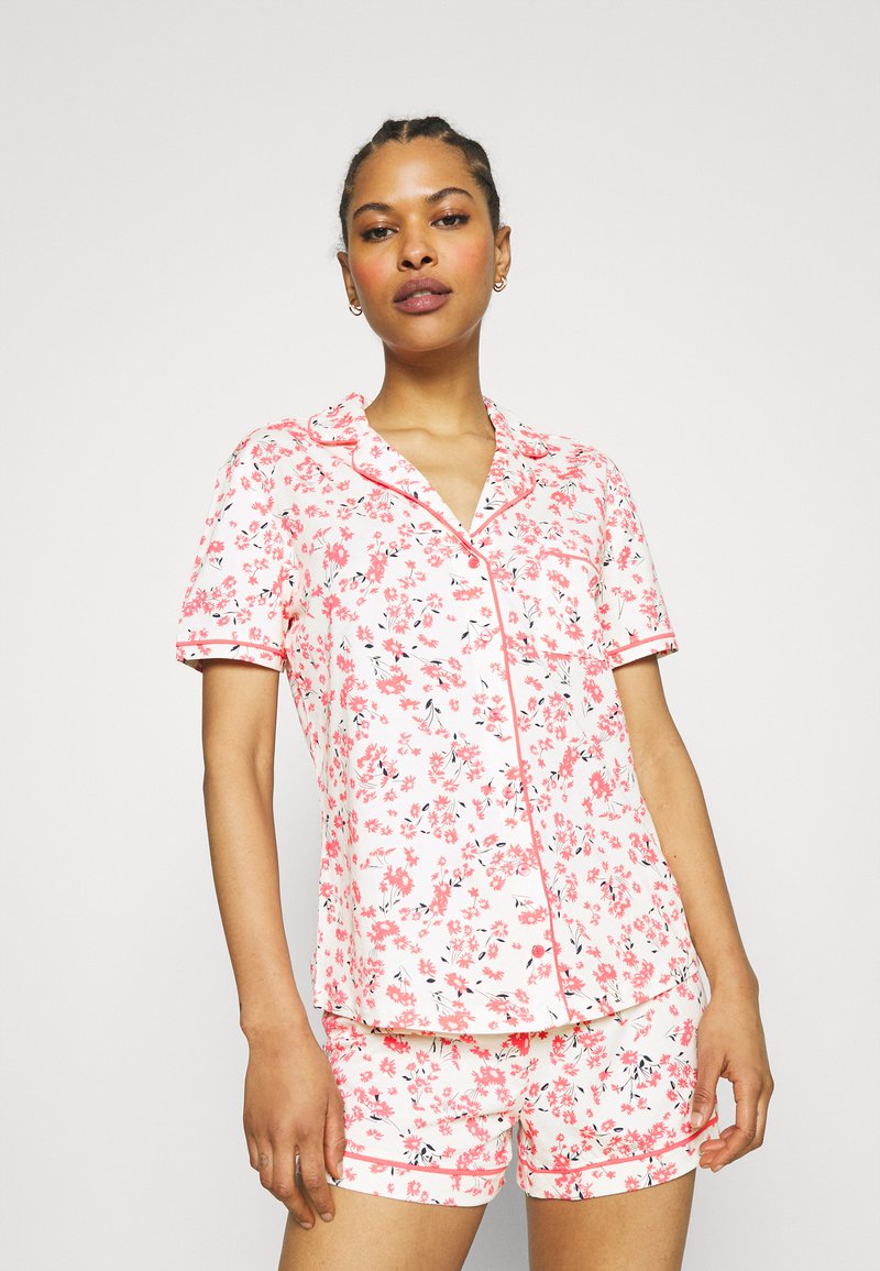 Pink floral pajama set made of soft fabric; short-sleeve top with notch collar and matching shorts, both featuring various colored flower patterns.