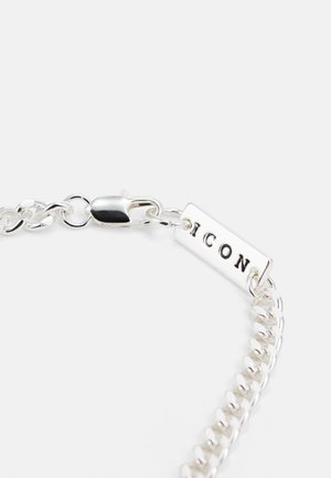 Bracciale in argento con una finitura liscia, caratterizzato da un'etichetta rettangolare incisa con la parola "ICON" e una chiusura a moschettone sicura.