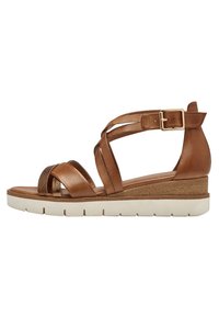 Brown leather wedge sandals featuring crisscross straps, textured accent, adjustable ankle strap, and a chunky white sole.