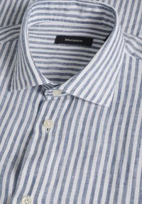 Camicia leggera a righe in lino blu e bianco. Presenta un colletto classico, una chiusura con bottoni e bottoni bianchi. Etichetta del marchio visibile all'interno.