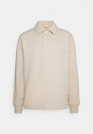 Polo beige a maniche lunghe con colletto appuntito e tre bottoni sulla patta frontale, polsini a coste e orlo dritto.