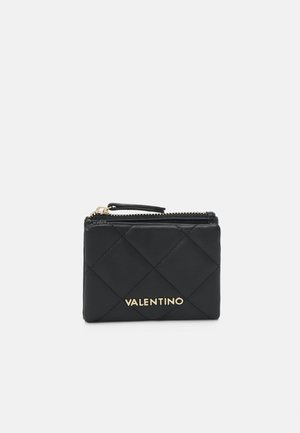 Schwarze, gesteppte Leder-Geldbörse mit goldfarbenem Logo. Mit Reißverschluss und kleinem Lederzugband. Kompakte rechteckige Form.