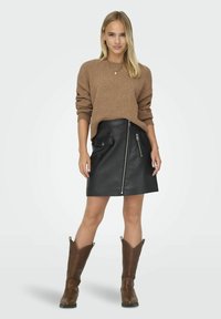 Maglione marrone con texture, gonna in pelle nera con zip e tasca frontale, e stivali da cowboy marroni. Materiali lisci con elementi di design distintivi.