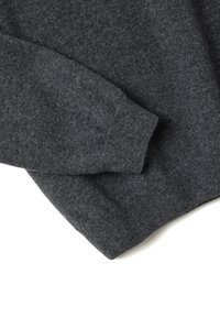 Maglione grigio in morbido tessuto lavorato a maglia, con un design semplice, scollo rotondo e polsini a costine per una vestibilità aderente.