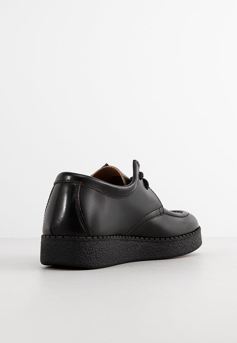 Chaussure en cuir noir avec un bout arrondi, semelle en caoutchouc texturé et coutures discrètes sur le côté. Design simple à lacets.