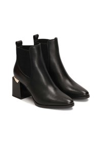 Botas de tobillo de cuero negro con punta afilada, paneles laterales elásticos y tacón cuadrado con un acento dorado. Textura suave en toda su superficie.