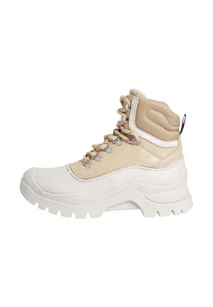 Sneaker alta con suola in gomma bianca, tomaia in tessuto beige, occhielli in metallo e allacciatura frontale. Accenti testurizzati sul colletto imbottito.