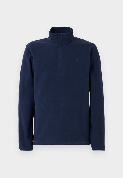 Pullover de fleece azul-marinho com gola alta, apresentando uma pala com botões e um pequeno logo no peito. Textura suave e mangas compridas.