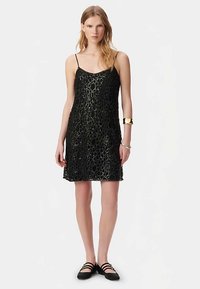 Zwarte jurk met een losse pasvorm, gemaakt van gestructureerde stof met een honingraatpatroon. Voorzien van dunne bandjes en een rechte zoom.