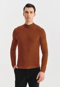 Brązowy sweter z długim rękawem i kołnierzem typu golf, wykonany z cienkiej dzianiny; charakteryzuje się dopasowanym krojem oraz prążkowanym kołnierzem i dolnym wykończeniem.