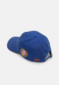 Cappellino di cotone blu con visiera curva, dotato di un patch ricamato rotondo e logo arancione sul retro. Cinturino regolabile sul retro.