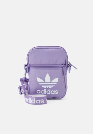 Mała fioletowa torba na ramię Adidas z białym logo trefoil, przednią kieszenią na zamek i regulowanym paskiem z logo na jednolitym tle.