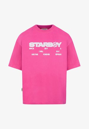 T-shirt à manches courtes rose vif avec texte blanc "STARBOY" et petits mots imprimés supplémentaires sur la poitrine.