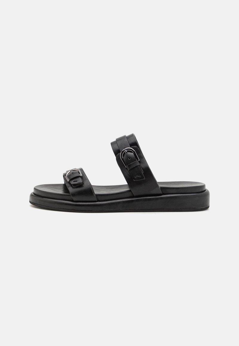 Black slide sandal made of leather with two adjustable straps, featuring metal buckles and a flat sole. Smooth texture and minimal design.