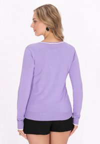 Lila langärmliger Pullover mit rundem Halsausschnitt und gerippetem Saum. Glatte Textur mit slim fit, kombiniert mit schwarzen Shorts.