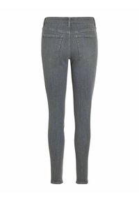 Jeans ajustados grises con una textura de denim suave, que presentan dos bolsillos traseros y una cintura de altura media, mostrados desde la vista trasera.