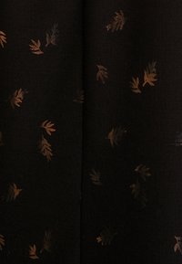 Tissu noir avec un motif de feuilles dispersées aux tons métalliques dorés et cuivrés. Texture lisse avec un éclat subtil.