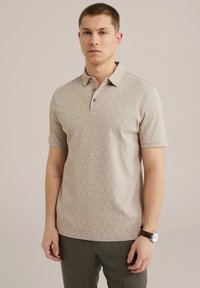 Camisa de polo beige con un patrón geométrico de diamantes, que presenta un cuello con solapa y tres botones. Fabricada en tejido suave y con mangas cortas.