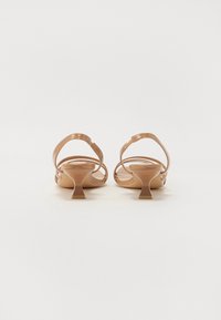 Nude sandaalit, joissa on matala paksupohja. Valmistettu sileästä materiaalista, ohut nilkkaremmien ja minimalistisen muotoilun kanssa.