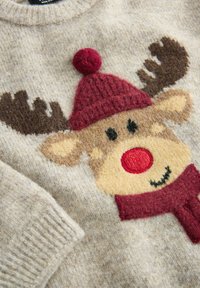 Strickpullover in hellbeige mit Rentier-Motiv. Verfügt über eine rote Pompon-Mütze, braune Geweih-Details und einen Schal, mit weichem Material und gestickten Details.
