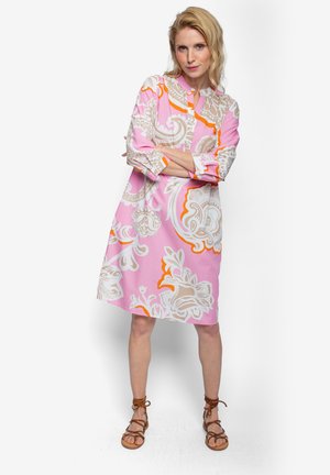 Różowa sukienka z długim rękawem w białe i pomarańczowe kwiatowe wzory. Posiada zapinany na guziki przód i luźny, rozkloszowany fason.