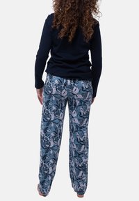 Siniset kukkakuosiset pyjamahousut, joissa valkoisia ja tummansinisiä kukkia; pehmeä kangas; väljä malli; joustava vyötärö; yhdistetty tumman pitkähihaisen paidan kanssa.